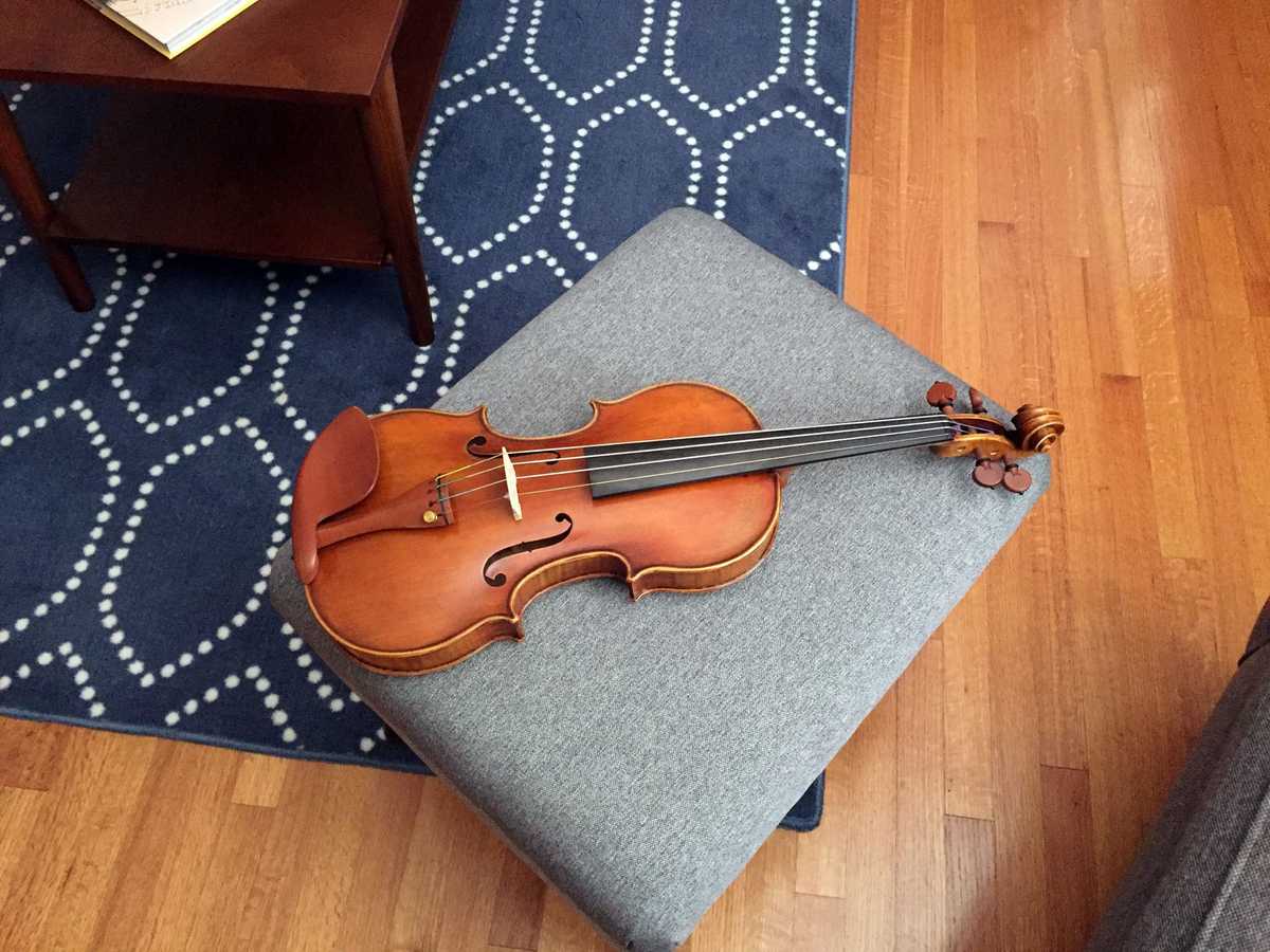 Picture of a brown violin sitting on a gray ottoman