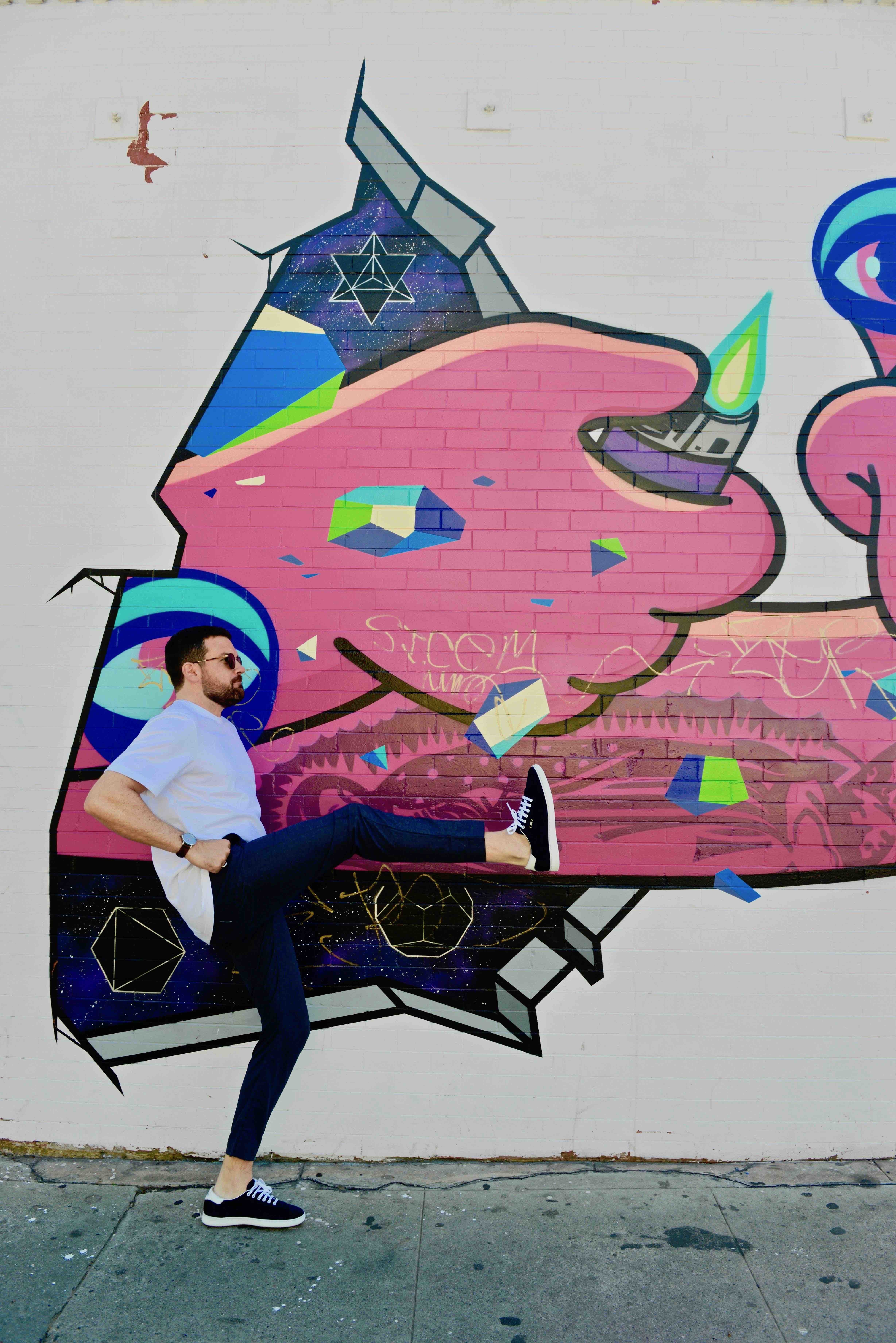 Adam kicking in front of mural
