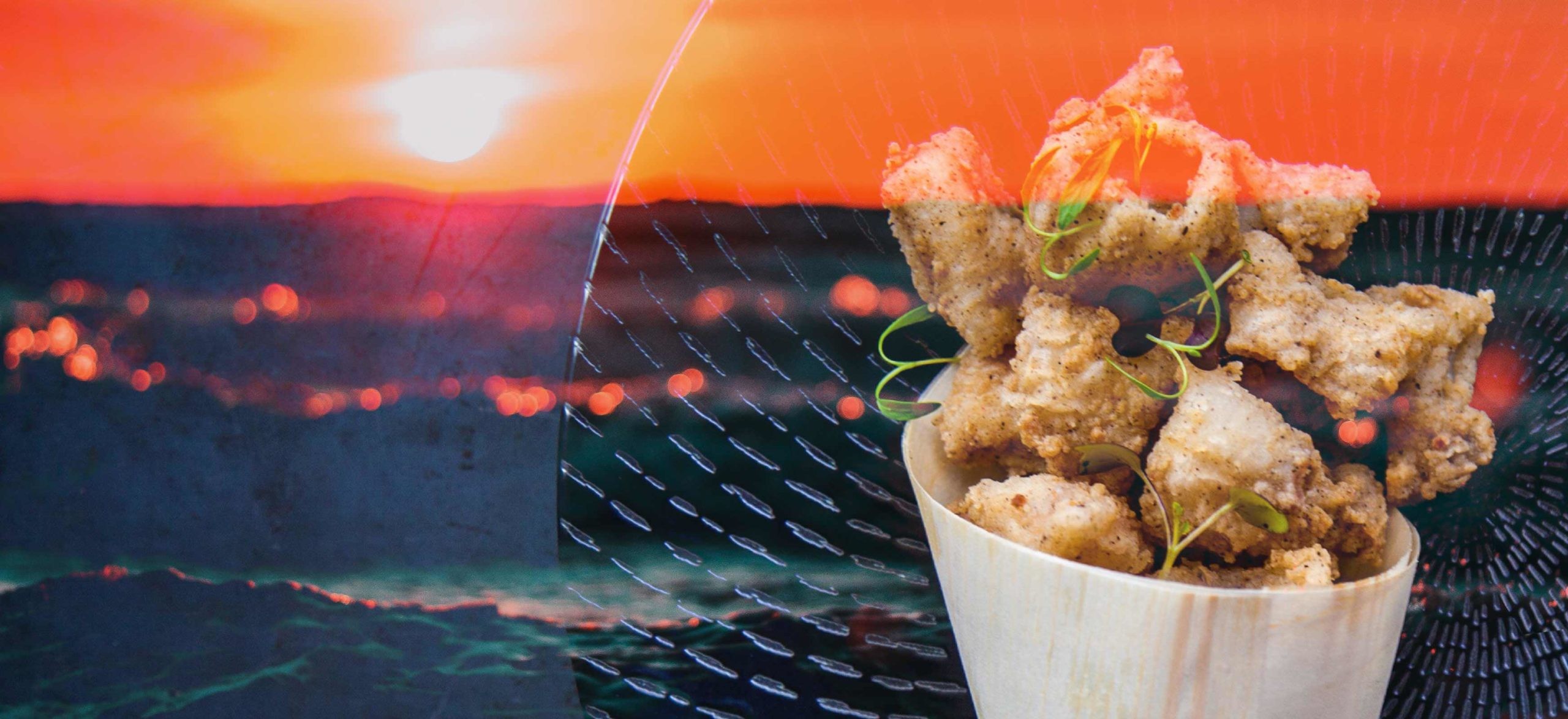 A photo of fried calamari with the ocean and sun in the background