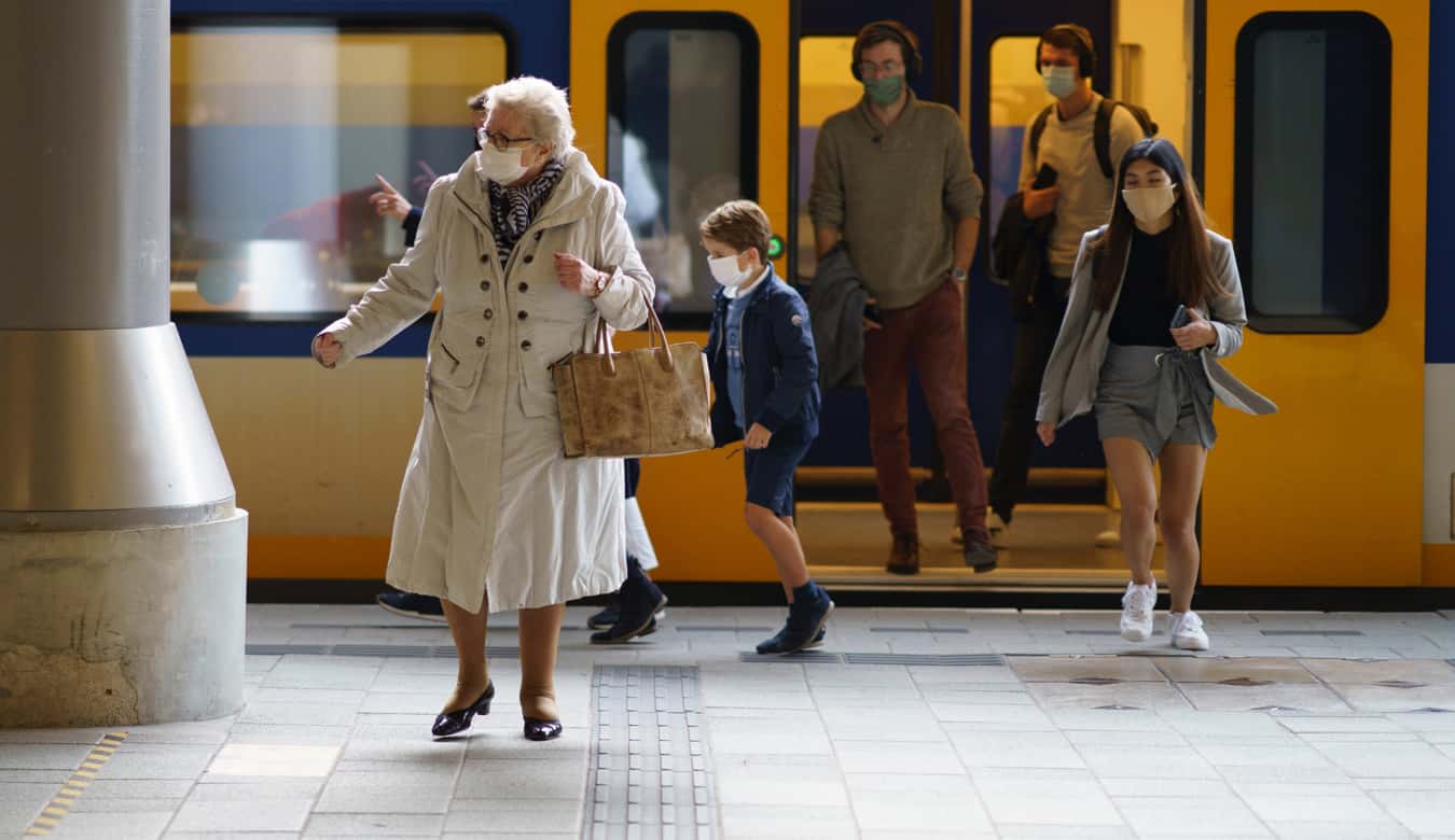 Elderly woman wearing a mask getting off a train