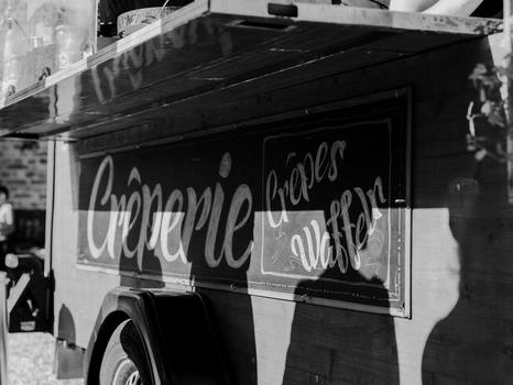 Schwarz-Weiß Aufnahme eines im Retrostil beschriebenen Crêperieschildes an einem Food Truck