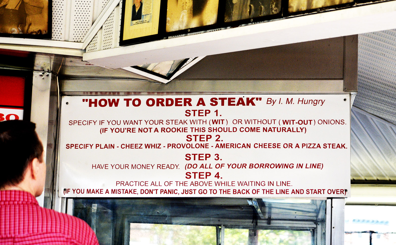 a red and white sign that explains how to order a cheesesteak