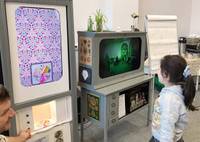 Child looking at large vertical screen showing kaleidoscope image of drawing.