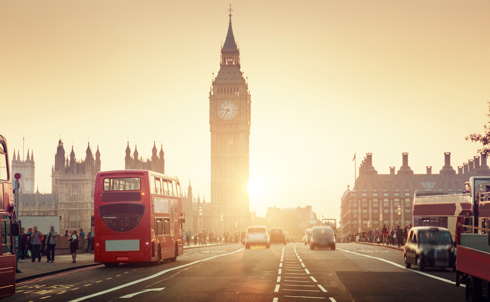 westminster bridge at sunset with the big ben clock tower and red double-decker buses