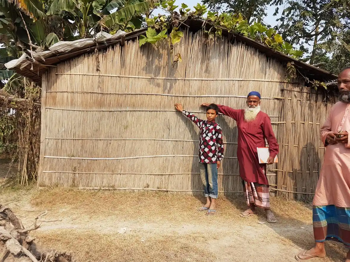 Community members in Bangladesh show the level of the flood water from the 2019 monsoon on their home
