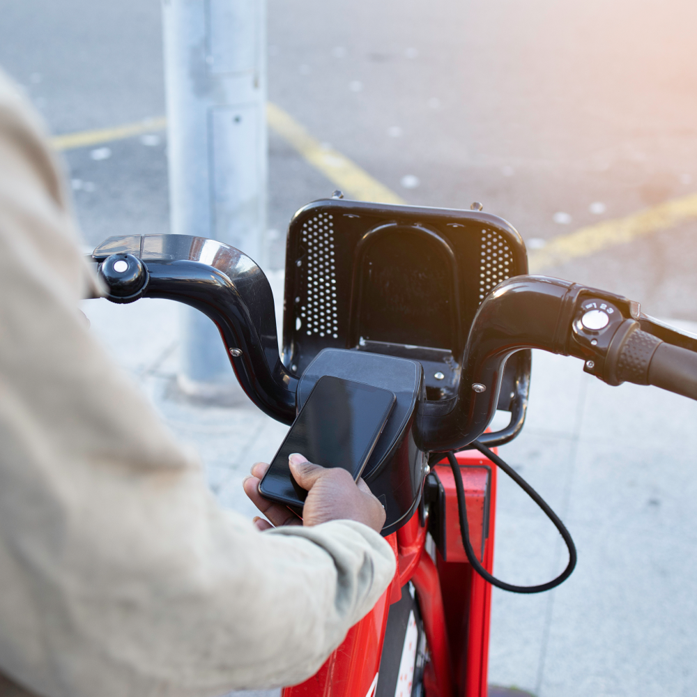 A caucasian man placing his mobile device on the front end of an ebike in order to check and use it.