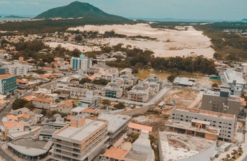 Foto aérea da para dos ingleses com vista dos apartamentos e dunas a direita e mar com faixa de area a esquerda.