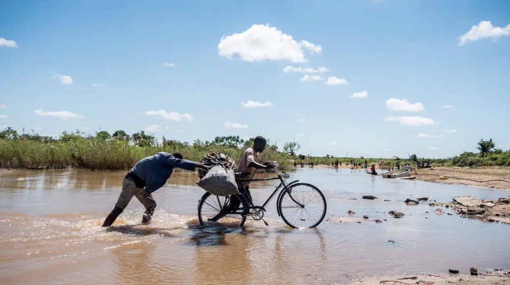 Joze Paulino and Gomez Dies push a bicycle loaded with charcoal across a flooded river near Nhamatanda, Mozambique.