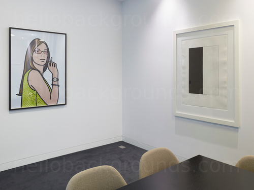 Basic meeting room featuring square black table with green fabric upholstered chairs next to wall mounted art pieces Zoom background
