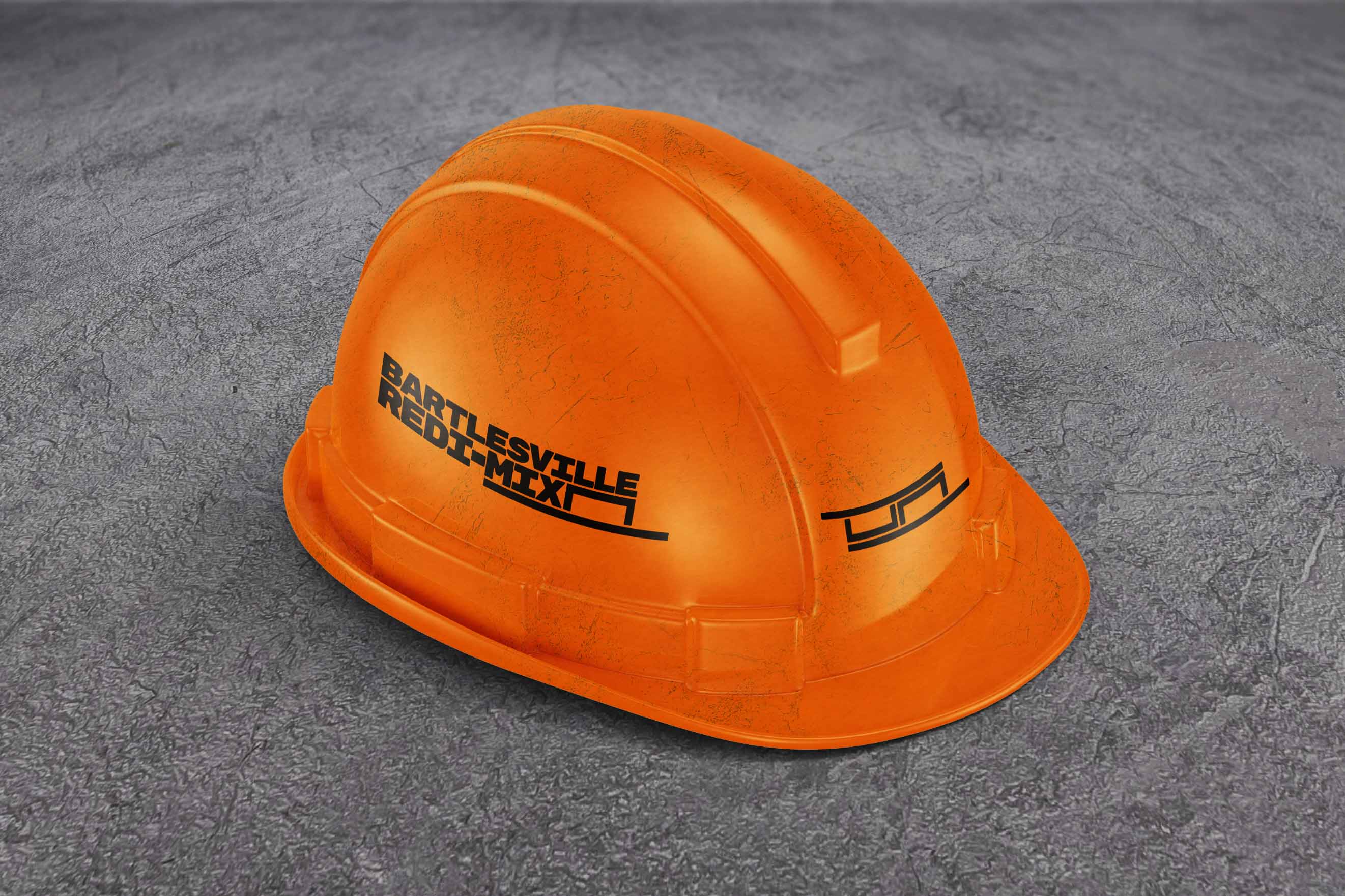 An orange hard hat featuring the Bartlesville Redi-Mix logo concept