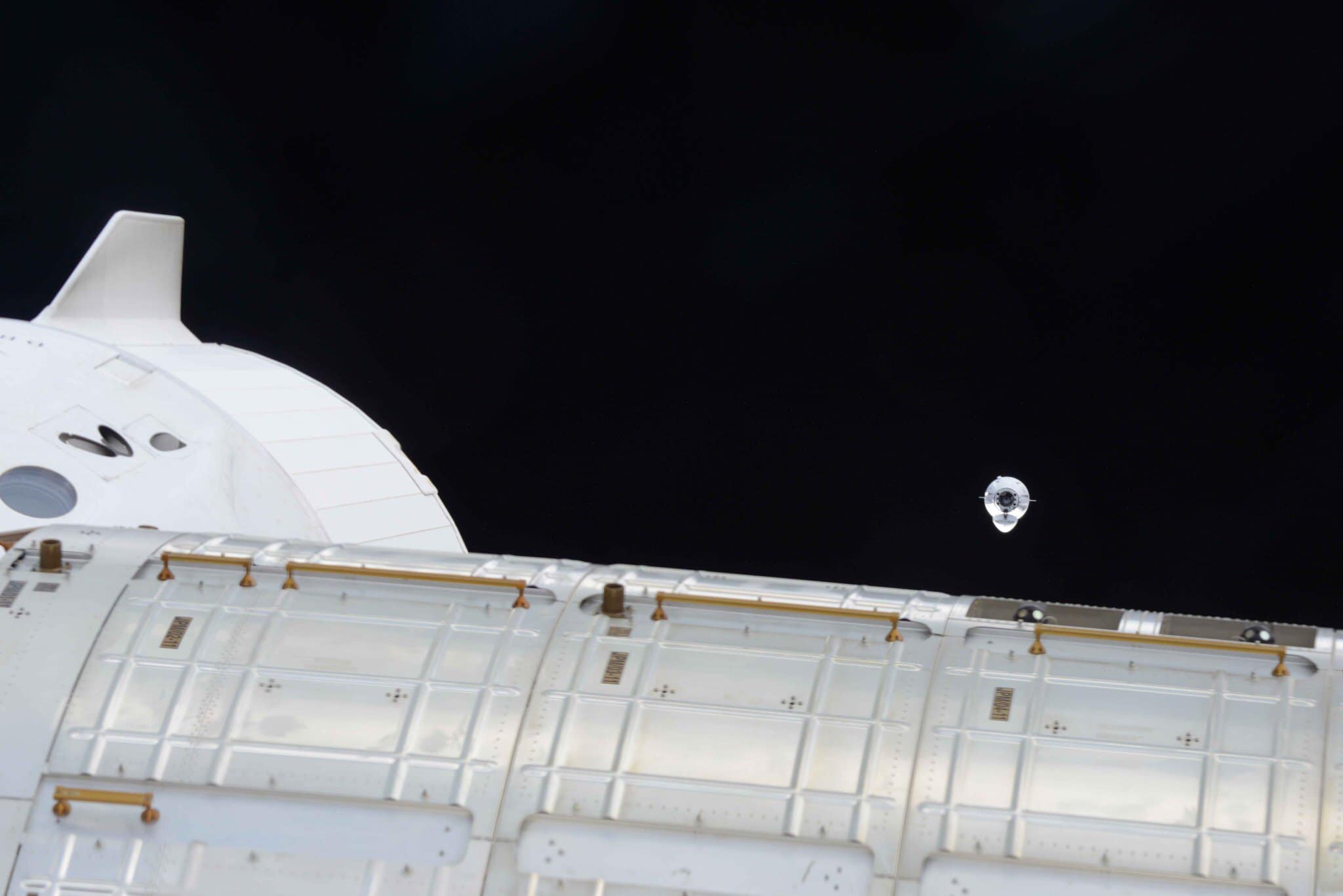 Imaginea 1: Capsula Dragon CRS-22 apropiindu-se de sasul IDA-3 al modulului Harmony pentru andocare, în timp ce în plan apropiat se vede andocată capsula Dragon Endeavour, folosită de echipajul misiunii Crew-2 (Sursa foto: NASA)