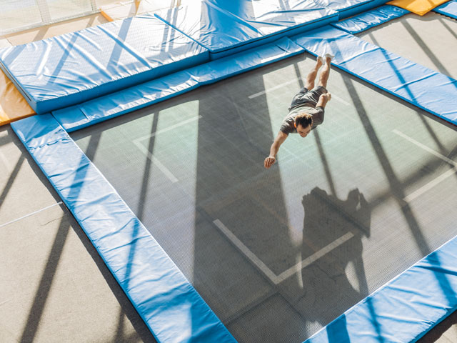 A single man doing a gymnastics routine on a trampoline