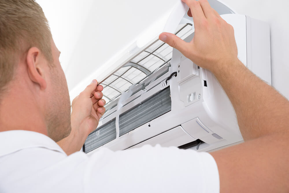 Photo of an HVAC repairperson fixing an AC unit