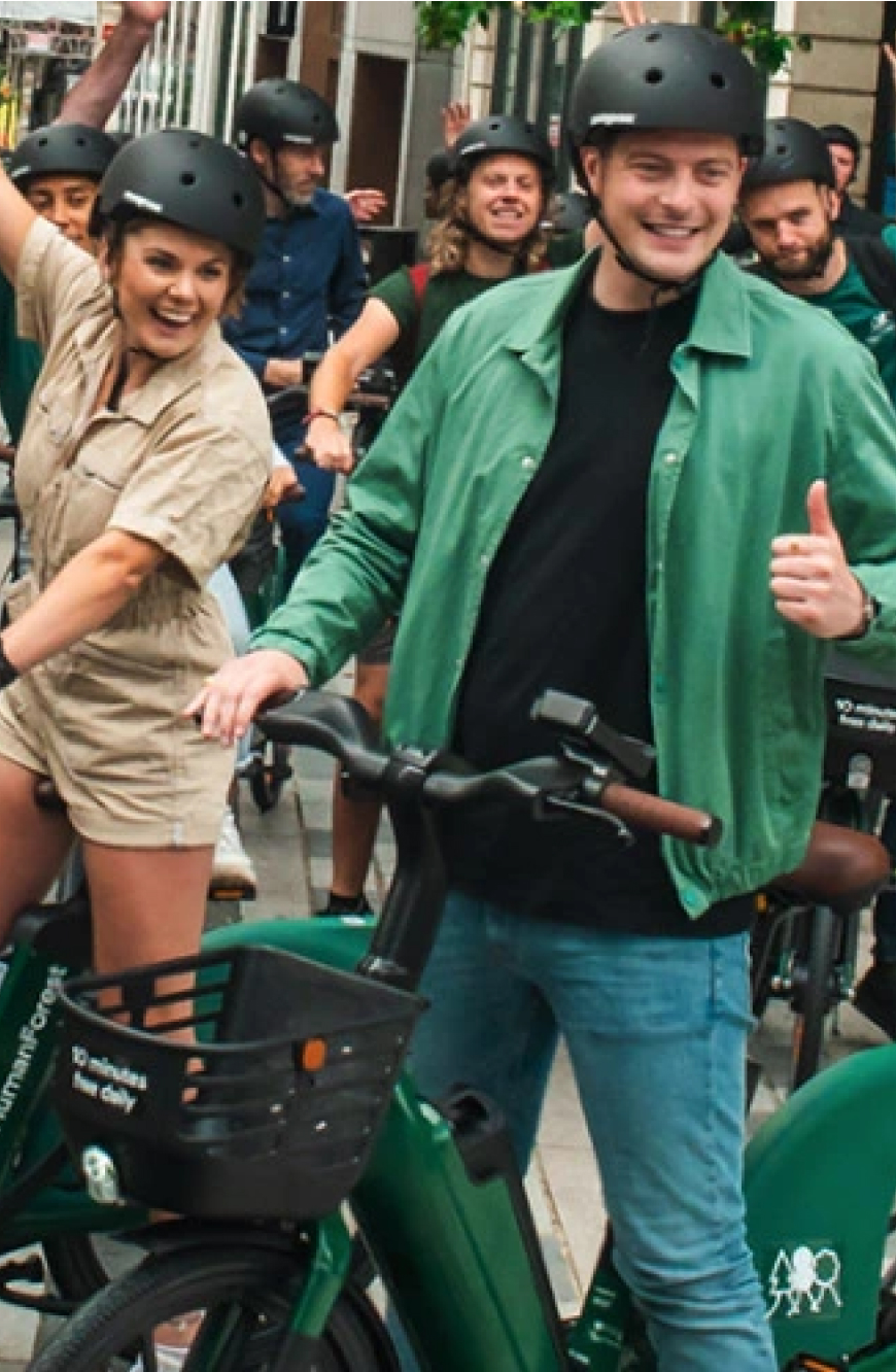 Human Forest customers hero carousel image featuring happy caucasian people standing together wearing helmets while riding ebikes.