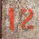 The digits one and two stenciled in orange onto rough concrete.