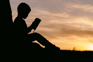 a boy reading at sunset