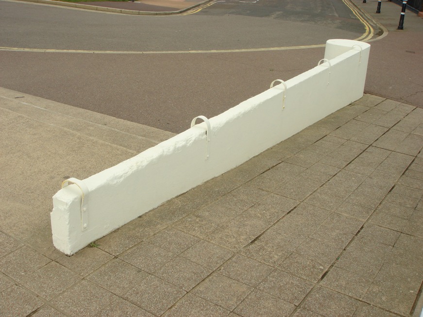 In England, a low concrete wall has its surface broken by looped metal rings placed every few feet, deterring skateboarders from its slope.