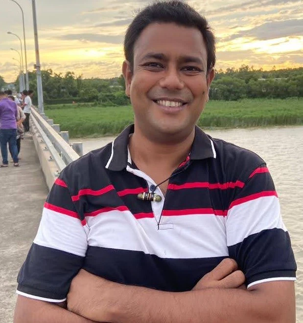 Ananda Iqbal standing on a bridge at sunset