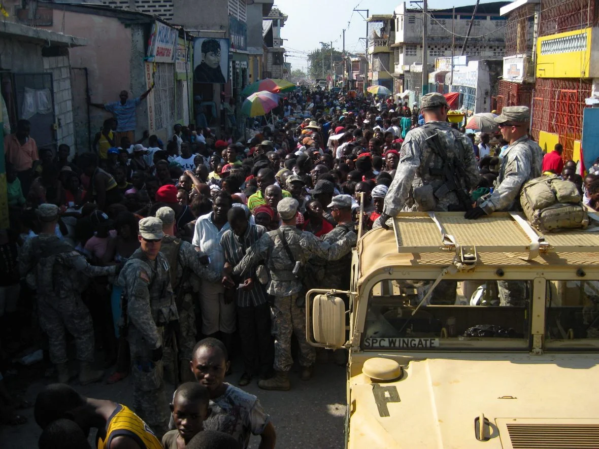 Military personnel and a crowd of Port-au-Prince residents.