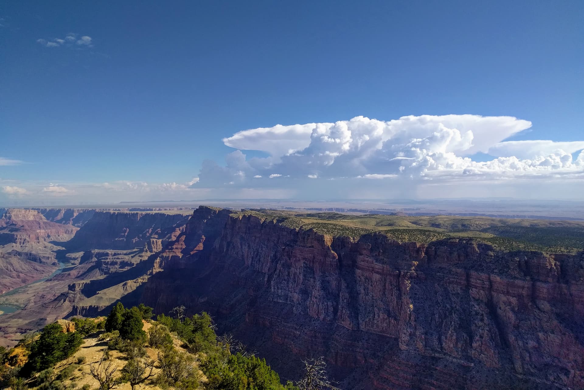 Looking across the South Rim of the Grand Canyon, and into the desert beyond. Rain clouds gather in the distance.