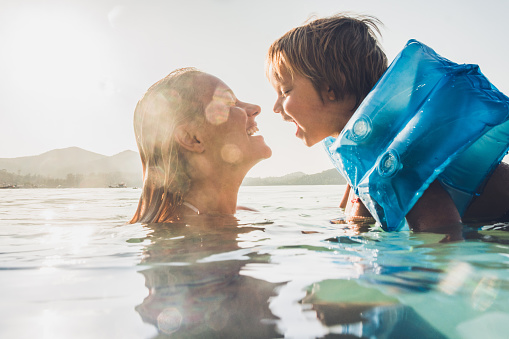 Happy mother and son having fun while swimming in sea on summer vacation.