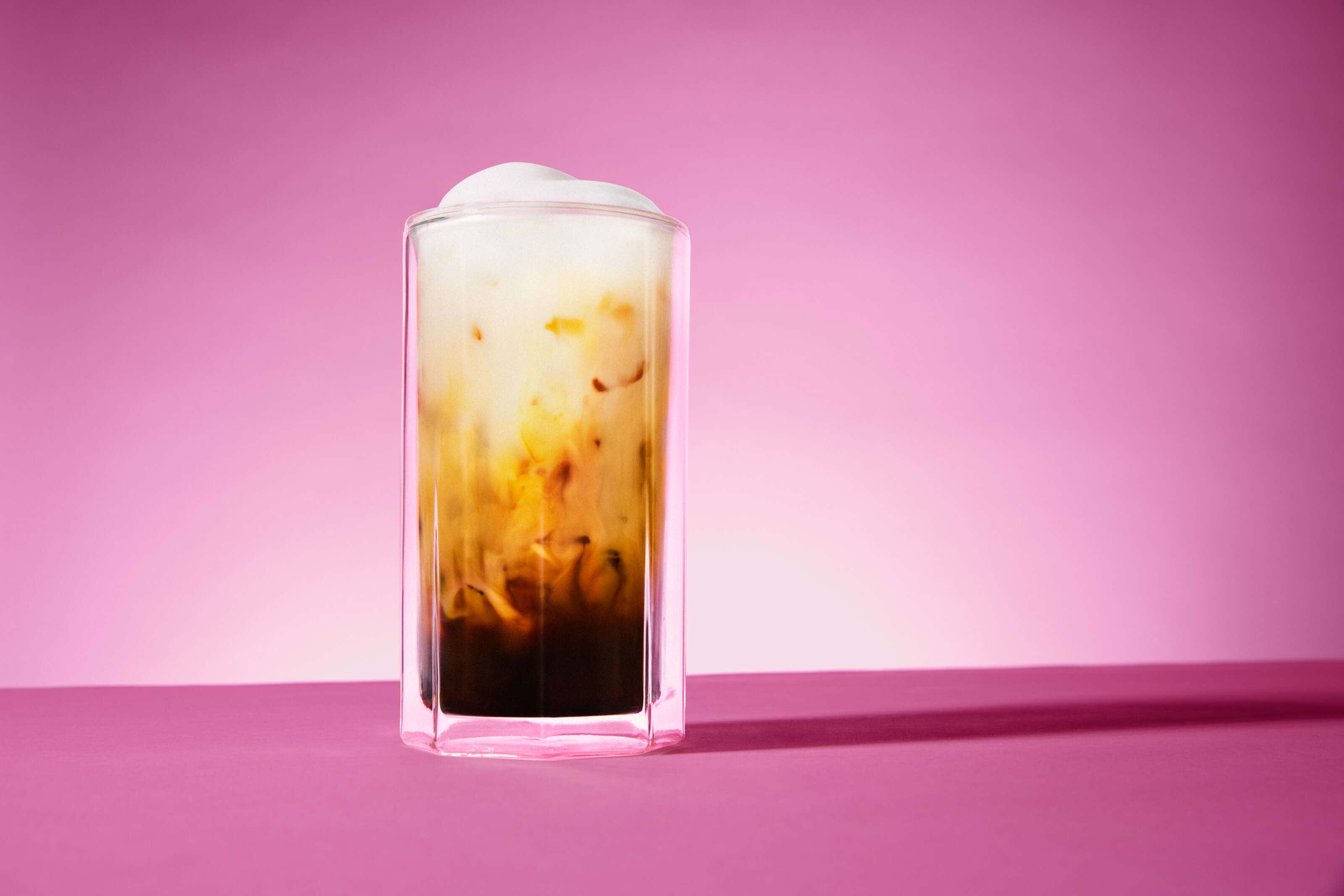iced coffee in a glass on a pink background