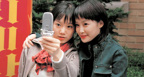 A screenshot from the movie 'Samaritan Girl' of two girls taking a selfie with an old cell phone.