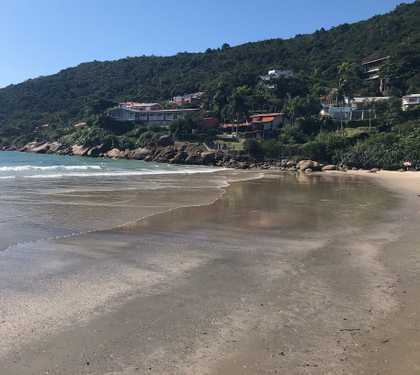 Faixa de area da praia da lagoinha do norte com vista das pedras e montanhas ao fundo.