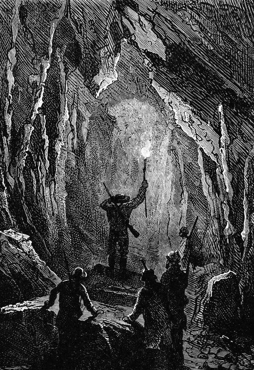 Engraved by Charles Barbant. A group of men stands at the entrance of a rocky tunnel. One of them has climbed onto a large rock lying on the ground and holds a torch high above his head, peering into the depths ahead of him.