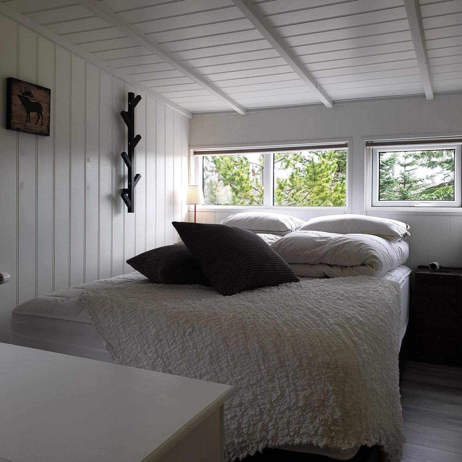 Skandinavischer Stil mit gemütlichem Doppelbett und weiß gestrichener Holzvertäfelung