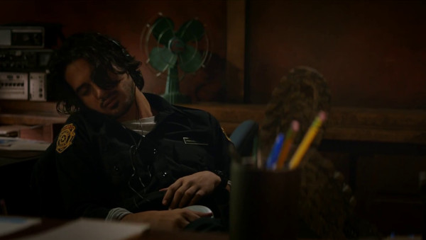 A still from Resident Evil: Welcome to Racoon City showing Leon napping at the RPD building front desk. He is reclined in his chair, with a Sony Discman playing music into Sony branded headphones.