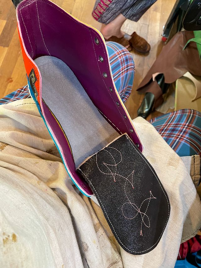 The shoe from above
on my aproned lap,
glued into the sole,
but still without laces.
The back of the tongue is sparkly black,
with a pink stitched scribble.
The inner lining is maroon leather.
