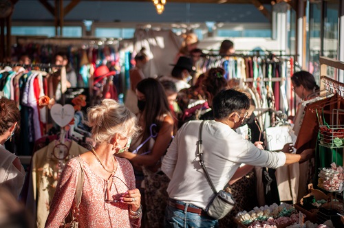 A crowd of people browsing through clothing racks