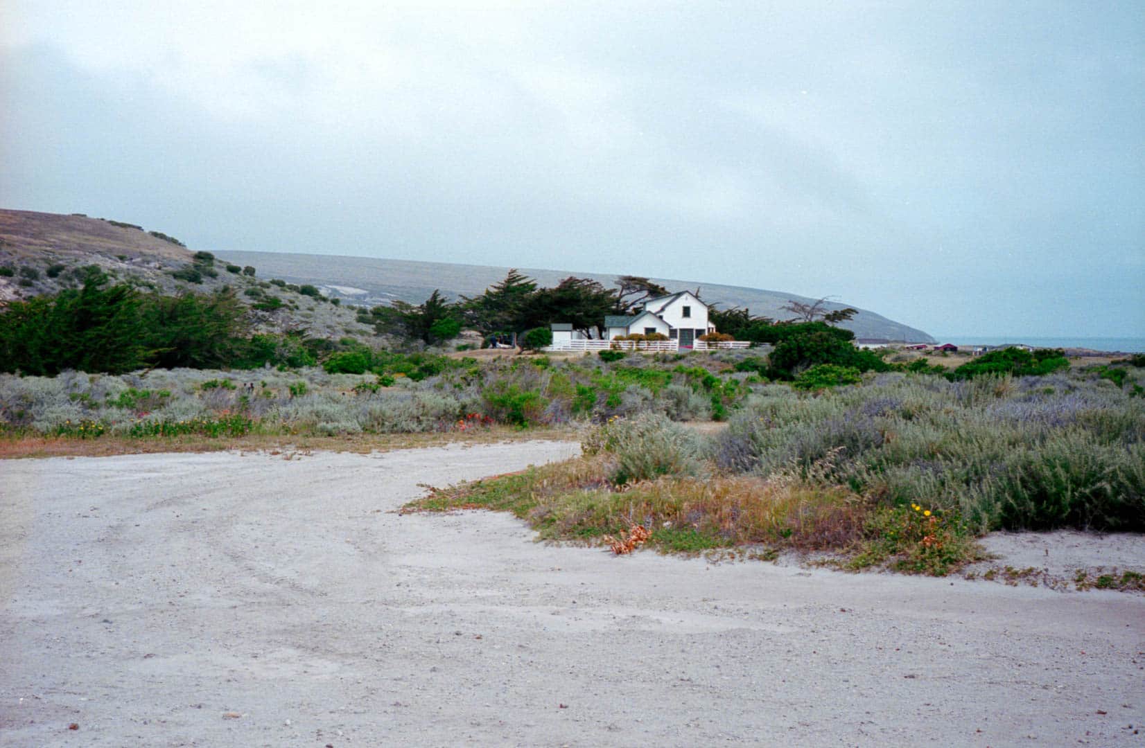 A white house in the distance amidst a grassy costal landscape