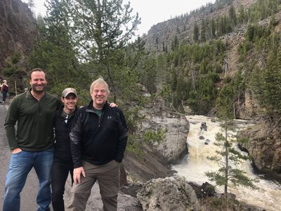 Three men posing in front of a waterfall, river in Yellowstone.