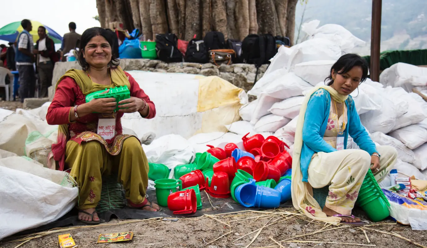 A woman organizes mugs at a Concern Worldwide and Rural Reconstruction Nepal (RRN) distribution in 2015 in Bhirkot, a village in Dolakha district, Nepal.