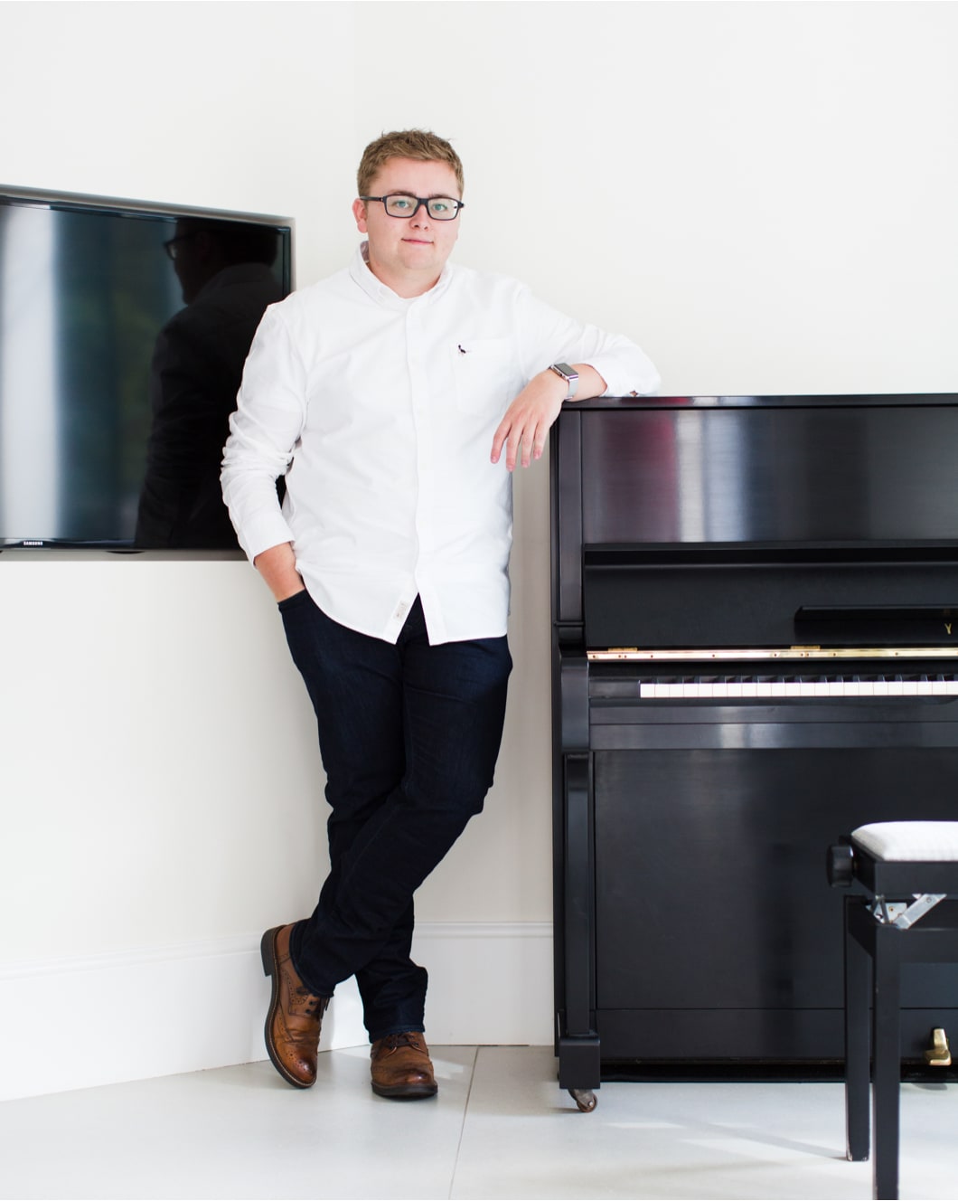 Jack Watkins, wedding pianist leaning on black Yamaha upright piano