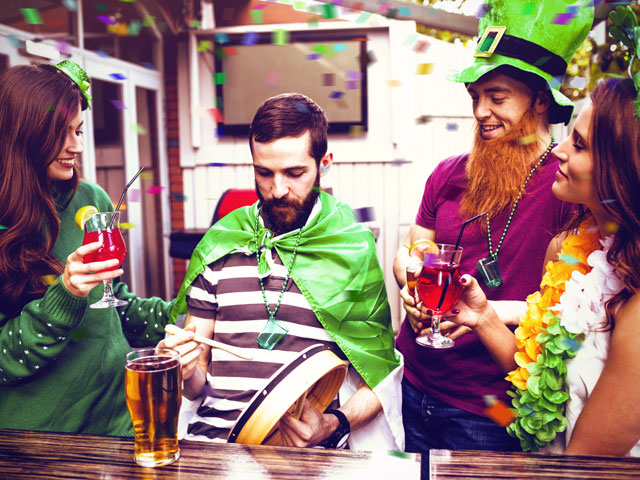 Four people dressed in green clothing playing drinking games on Saint Patrick's Day