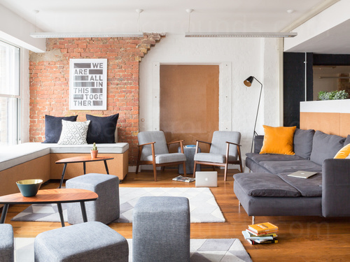 Spacious meeting room with bare red-brick walls and wooden flooring featuring various blue shaded seating Skype background