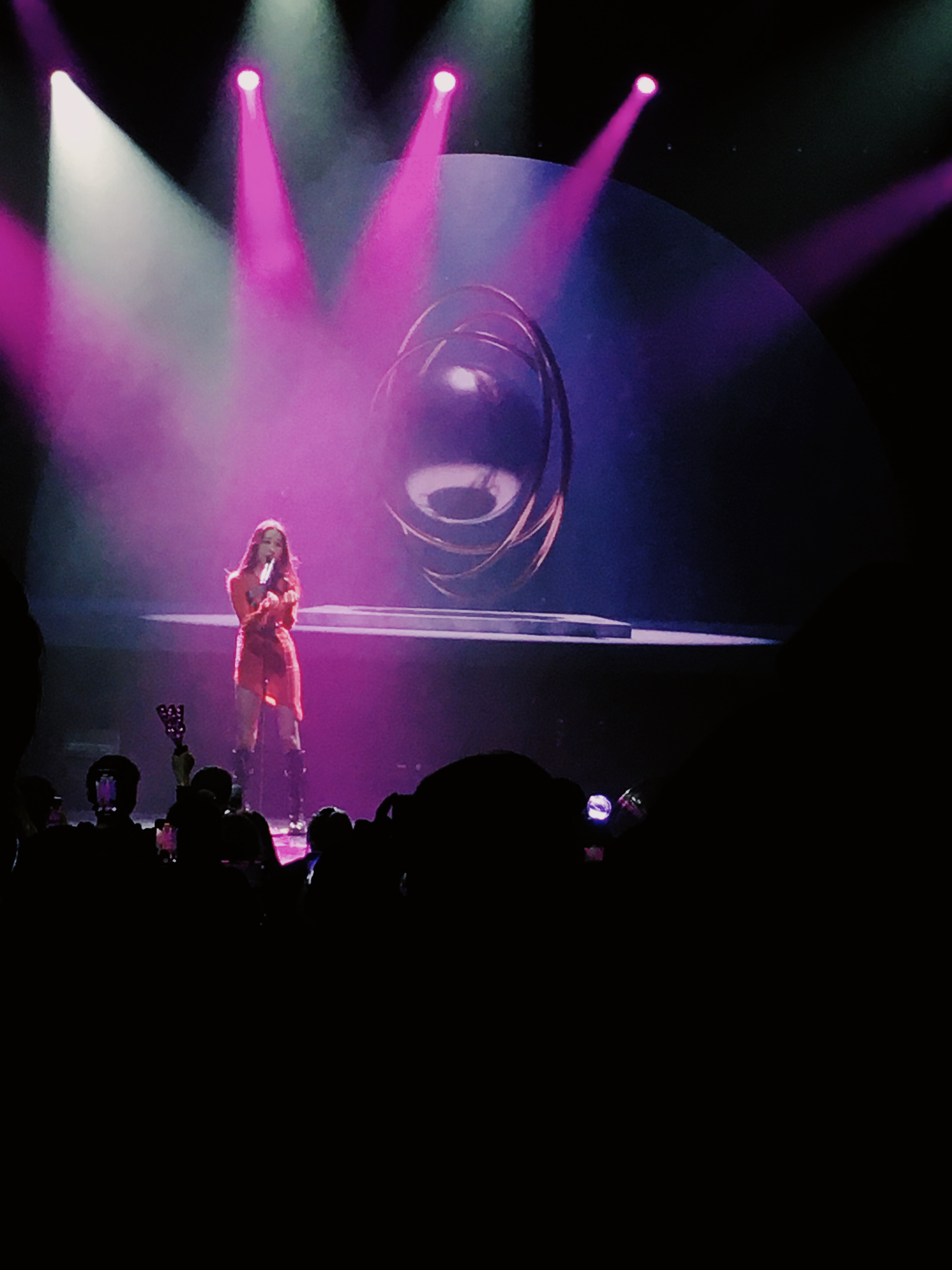 Zoomed in concert photo of Sunmi as she's singing under purple and blue lights.