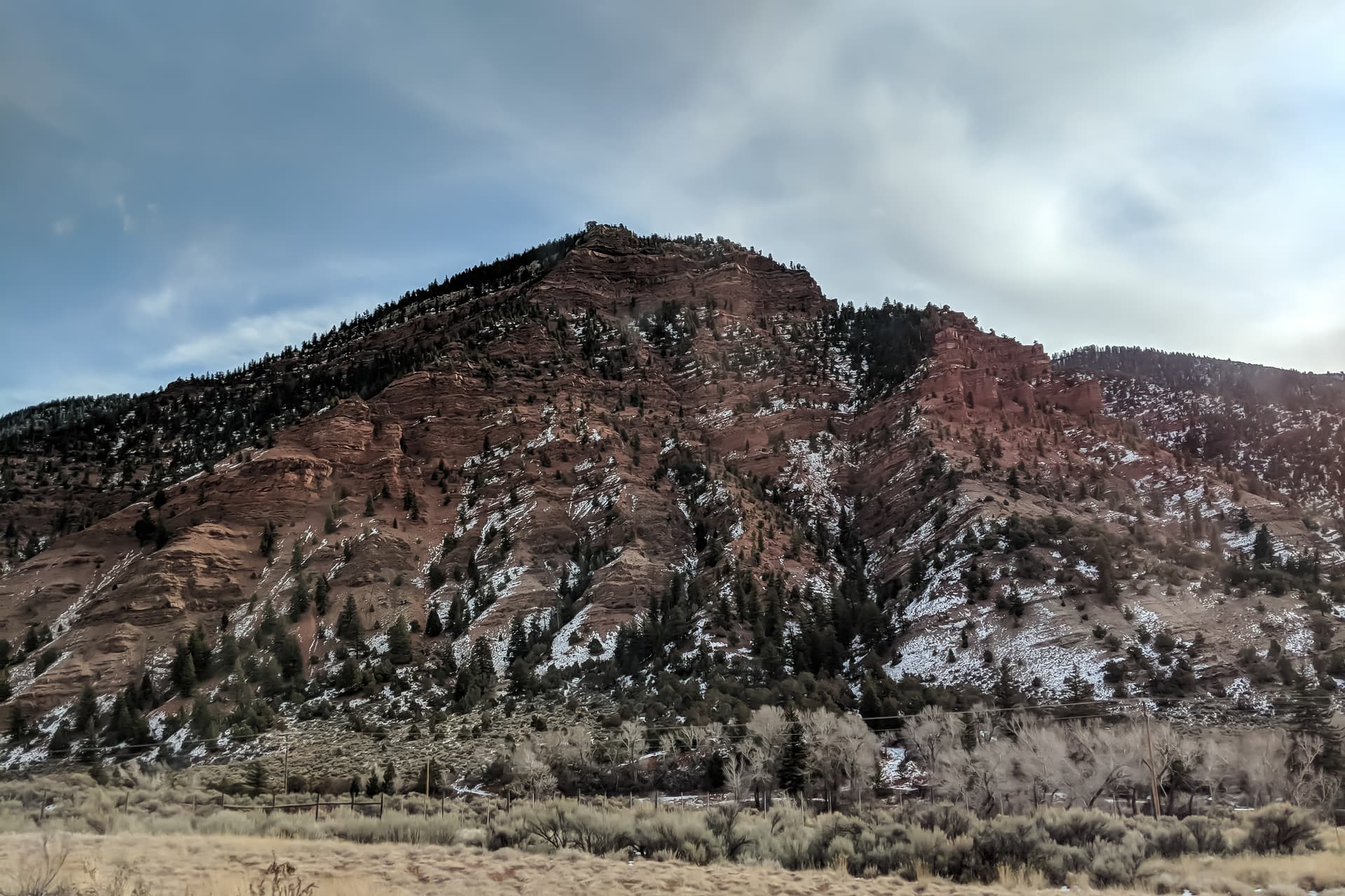 A small peak of red stone next to a mountain highway. Despite obviously being a winter scene, there is remarkably little snow on the ground.
