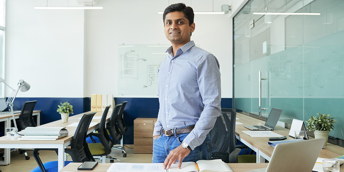 What is a UX audit? A UX designer presenting the findings of a UX audit A UX designer standing in front of a desk, smiling at the camera