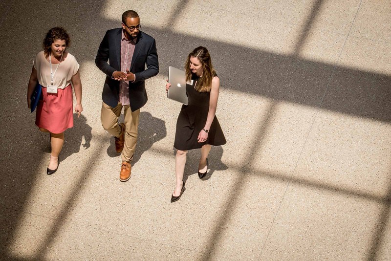 A trio of American University students walking to a campus event underneath a skylight