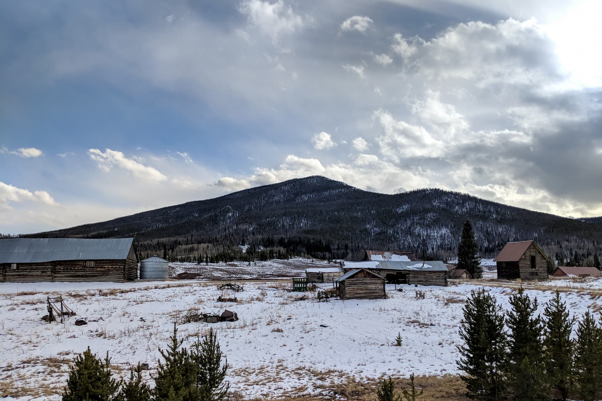 Looking out across a snowy high country ranch. A small mountain rises behind the ranch buildings.
