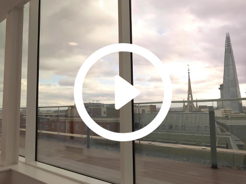 Modern roof terrace through large window with wooden decking holding urban city skyline views including The Shard skyscraper Google Meet background