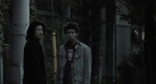 A wide screenshot from the film 'Bright Future' of two men, Yuji and Mamoru, looking into the camera anxiously.