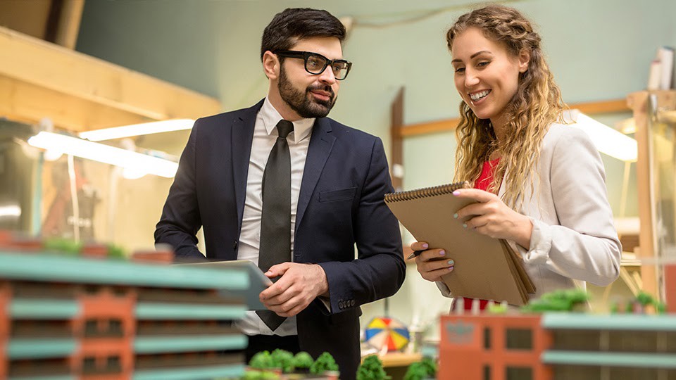 Male and female social workers looking at a clipboard noting city planning topics.