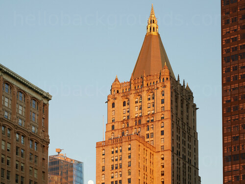 Urban ornate tall building in golden sunset light against clear blue sky Google Meet background