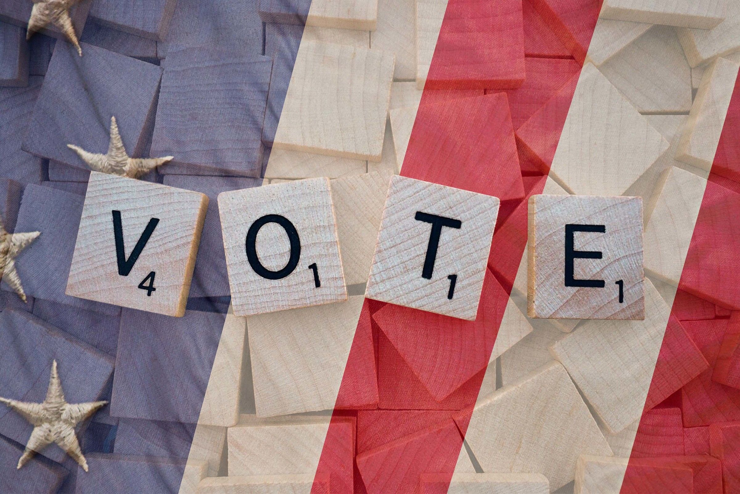 scrabble letters spelling “vote” with american flag in the background