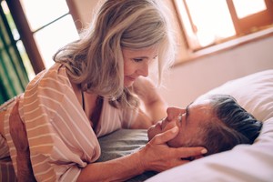 Senior couple flirting and looking in each other's eyes with desire while relaxing in bed birth control method for men vasectomy